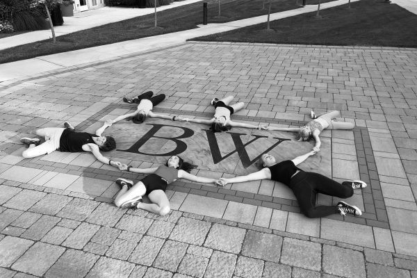 dancers laying in a circle on the ground with hands linked on BW logo