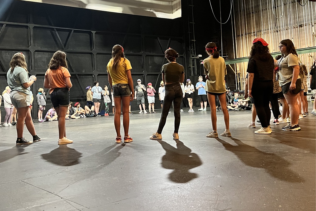 students on stage standing in a large circle